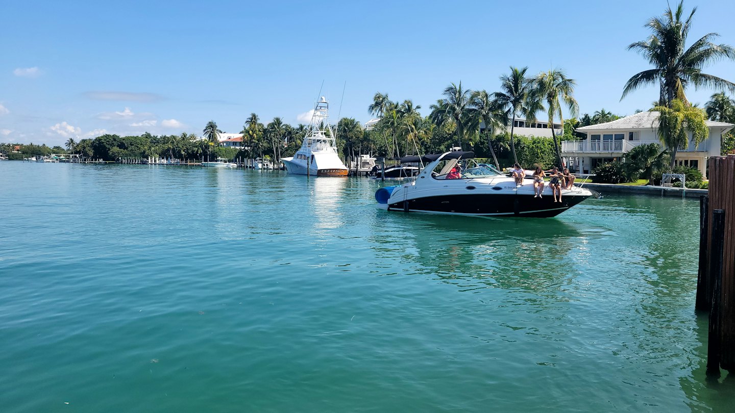 Friends relax on a motorboat cruising near a tropical shoreline.