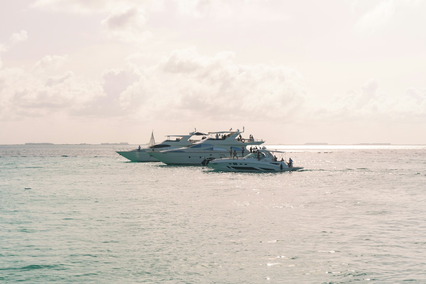 Luxury yachts and speedboats floating on calm turquoise water.